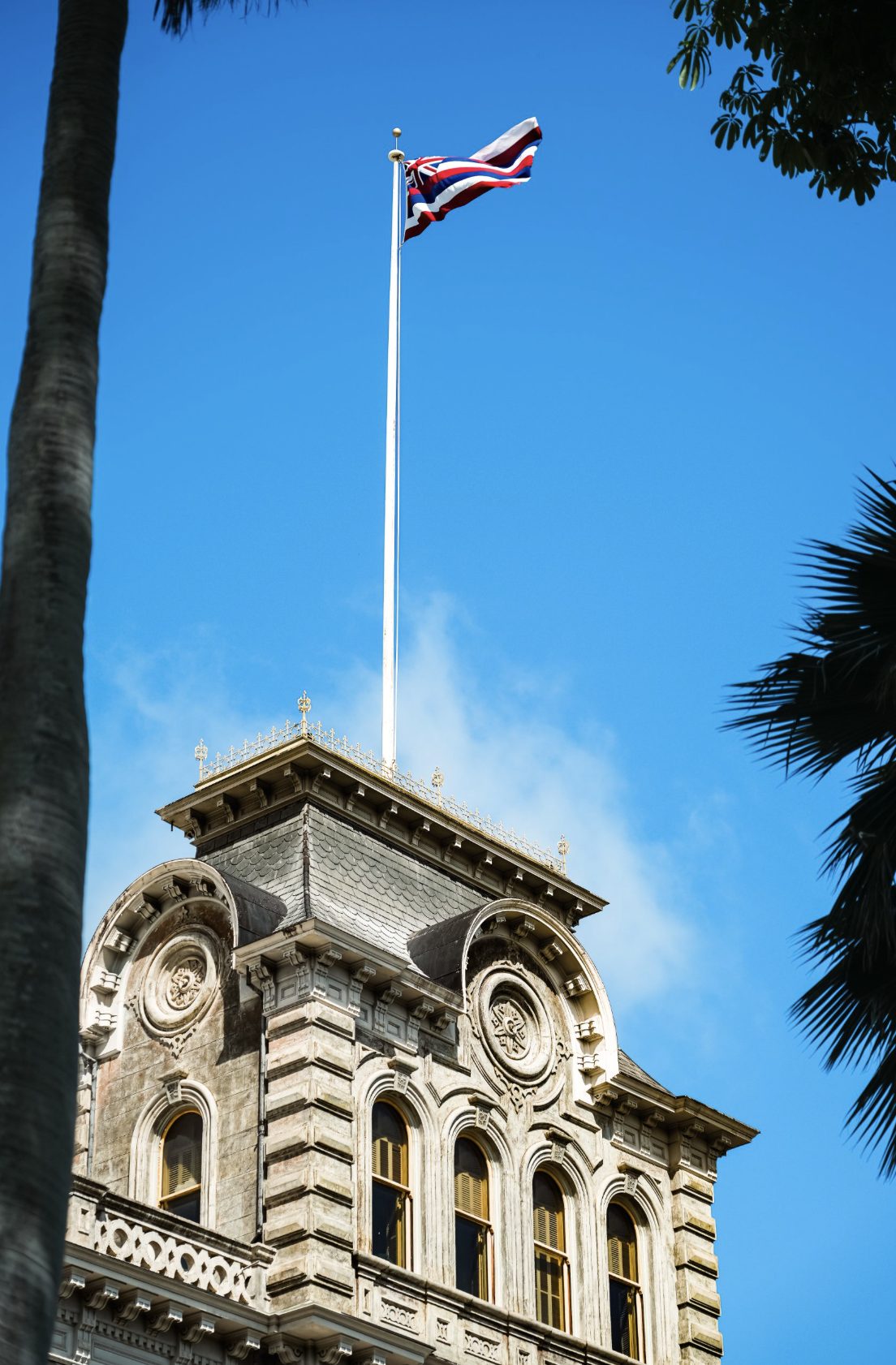 The Hawaiian state flag flying above Iolani Palace in downtown Honolulu, Oahu